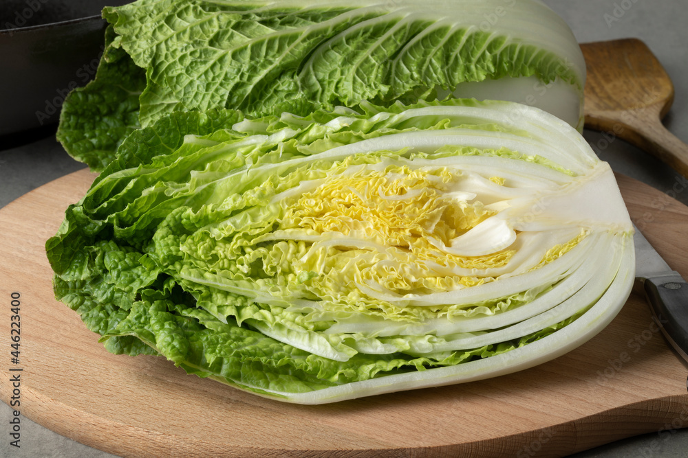 Whole and half fresh raw Chinese cabbage close up on a cutting board Whole and half fresh raw Chinese cabbage close up on a cutting board