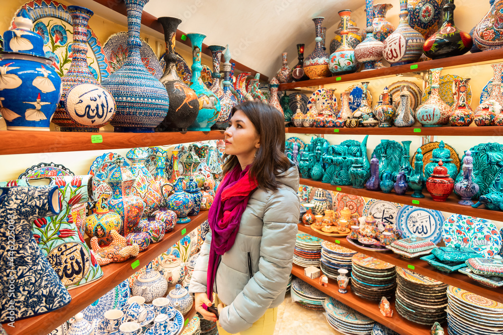 Young woman looking at Turkish colorful ceramic plates and jugs at the store
