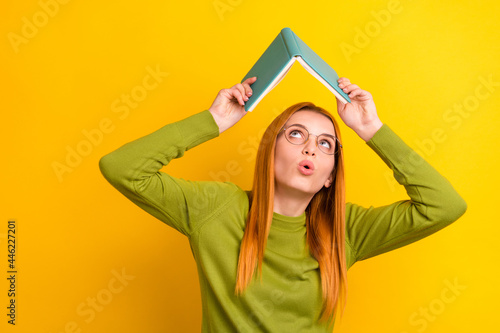Photo of curious ginger hairdo millennial lady read book wear green sweater spectacles isolated on yellow color background