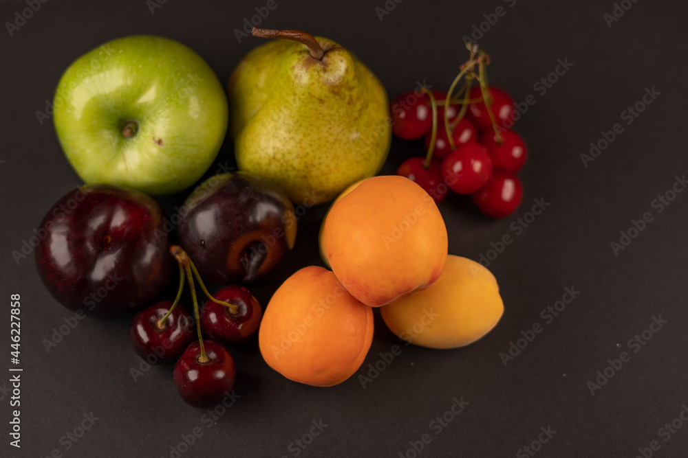 Fresh fruits and dried fruit powder. Pear, apple, apricot, cherry, currant, strawberry and plum on dark paper background. Vegetarian healthy detox food. Fresh fruits and dried fruit powder. Pear, apple, apricot, cherry, currant, strawberry and plum on dark paper background. Vegetarian healthy detox food.