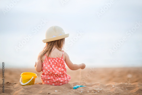 Fototapeta Naklejka Na Ścianę i Meble -  baby girl is sitting on beach and playing in sand in summer. holidays with children