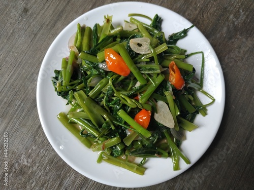 green oseng kangkung or stir fry on a white plate, a favorite food in Indonesia photo