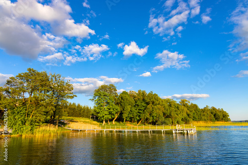 Fototapeta Naklejka Na Ścianę i Meble -  Panoramic summer view of Jezioro Selmet Wielki lake landscape with vintage pier reeds and wooded shoreline in Sedki village in Masuria region of Poland
