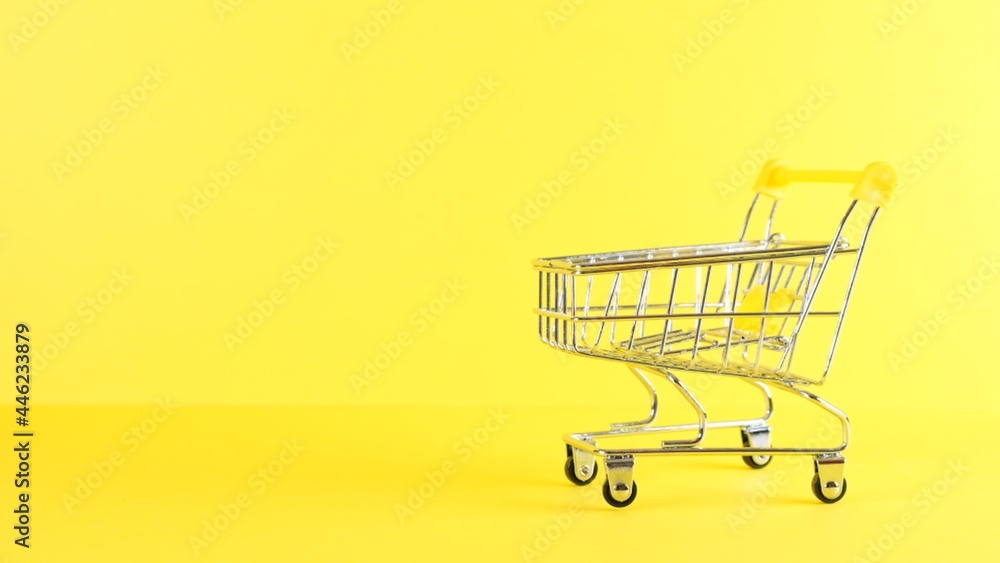 empty Shopping cart on a yellow background, closeup. Black Friday Shopping and Discount Concept