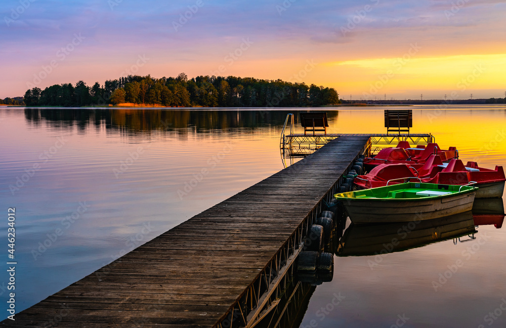 Panoramic summer sunset view of Jezioro Selmet Wielki lake landscape with boat pier and wooded island in Sedki village in Masuria region of Poland