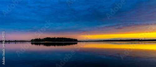 Panoramic summer sunset view of Jezioro Selmet Wielki lake landscape with wooded island in Sedki village in Masuria region of Poland