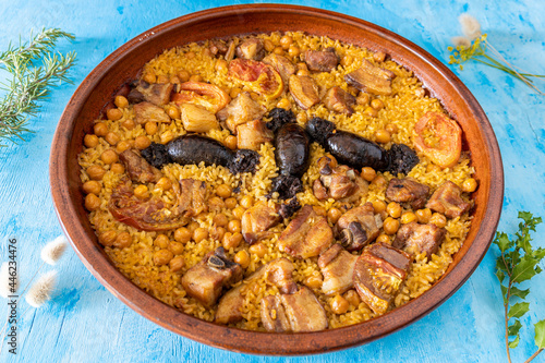 Baked rice in clay pot on a blue background. Typical dish of Valencian gastronomy. photo