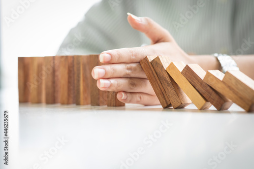Close up of hand stopping wooden domino business crisis effect or risk business protection concept,