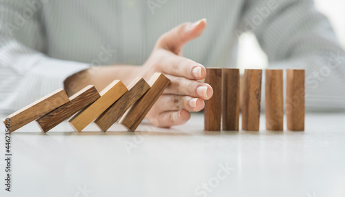Close up of hand stopping wooden domino business crisis effect or risk business protection concept,