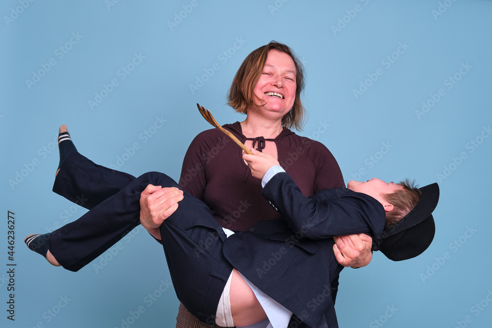 Mom holds an adult son of a schoolboy in her arms, studio blue background Mom holds an adult son of a schoolboy in her arms, studio blue background