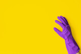Hand in a purple rubber glove on a yellow background. Cleaning concept, cleaning service. Banner. Flat lay, top view