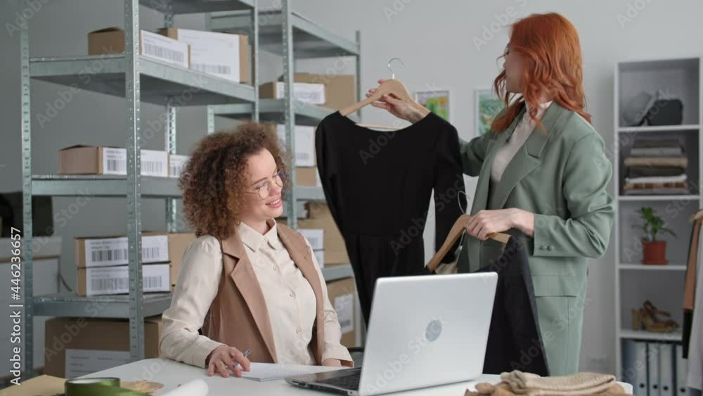 online shop, a charming saleswoman with a female colleague sells a dress through an online store using modern technology video communication on a laptop communicating with a buyer, small business online shop, a charming saleswoman with a female colleague sells a dress through an online store using modern technology video communication on a laptop communicating with a buyer, small business