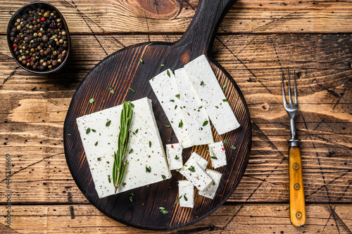 Cut cheese feta with rosemary on a wooden cutting board. wooden background. Top view