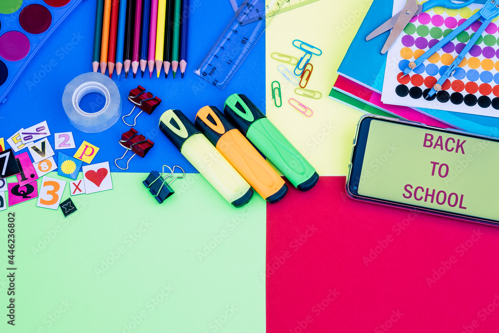 Group of items for back to school on colorful background,  pencils, notebooks, scissors, elements and message on smart phone - education concept, copy space
