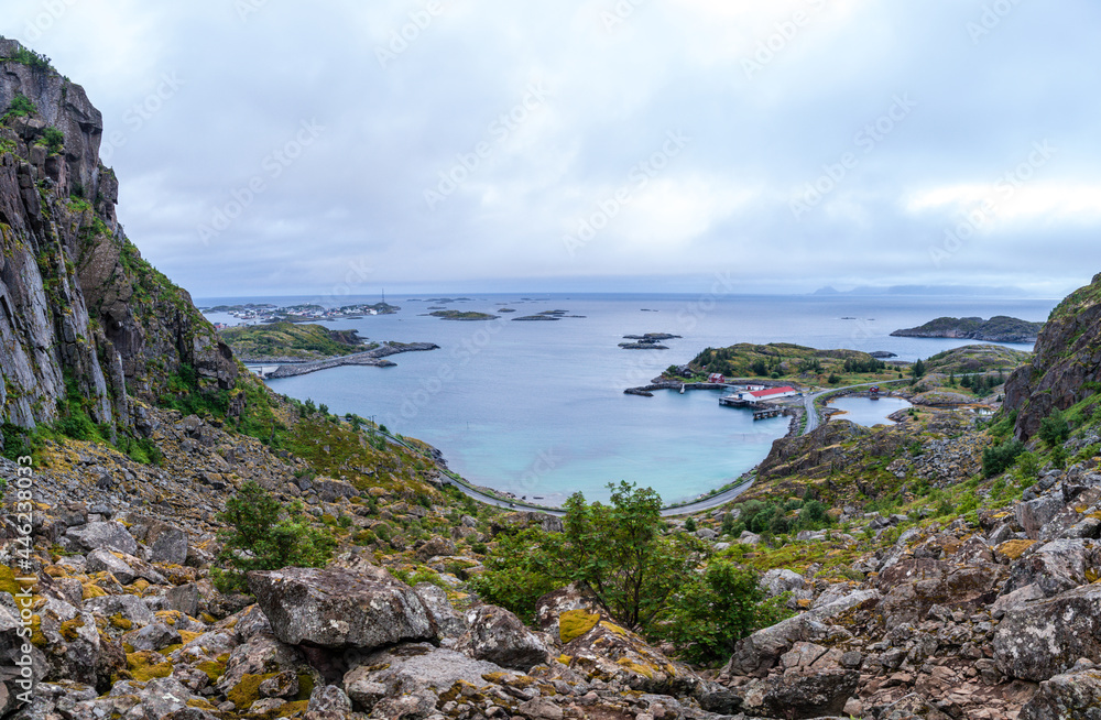 View from above from a cliff on the ocean and on blue panorama of mountains and Reine in Lofoten islands, Norway