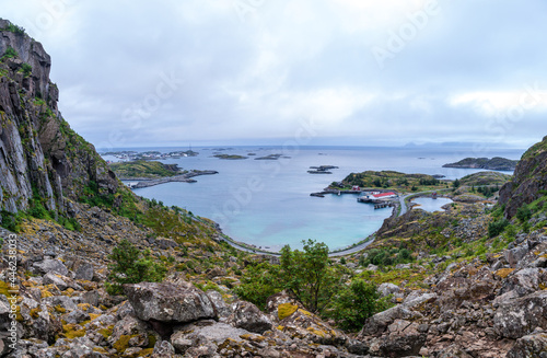 View from above from a cliff on the ocean and on blue panorama of mountains and Reine in Lofoten islands, Norway