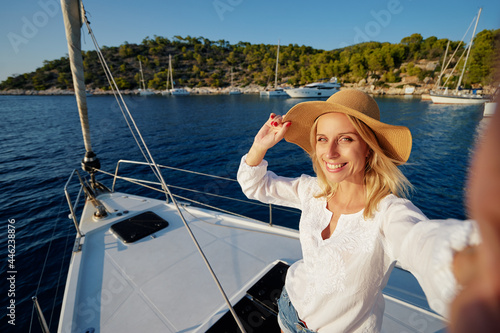 Luxury travel on the yacht. Young happy woman taking selfie on boat deck sailing the sea. Yachting in Greece. © luengo_ua