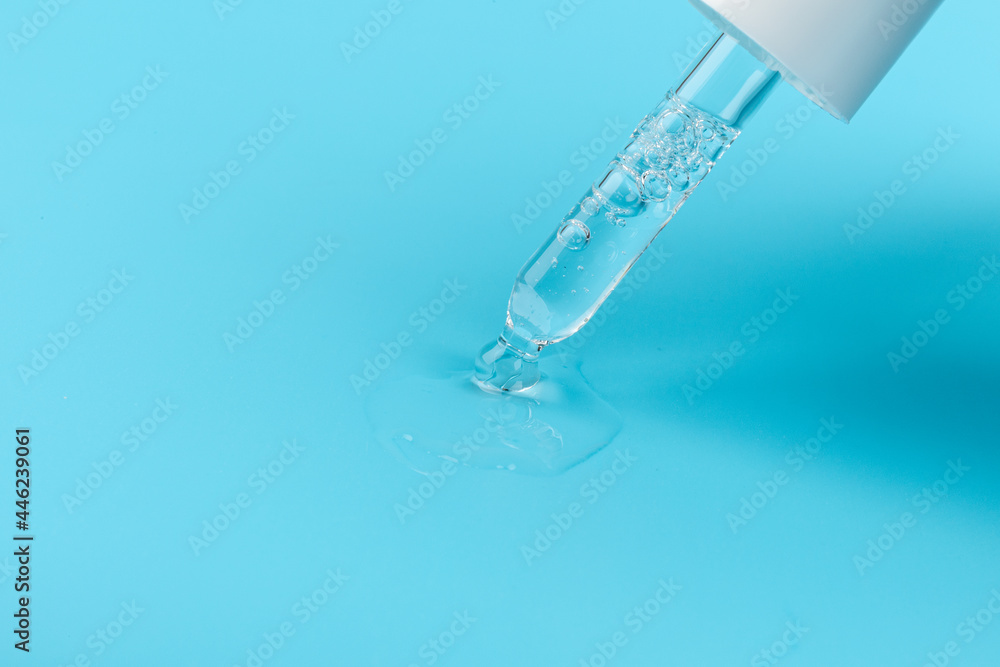 face serum drop with bottle on blue background. face serum drop with bottle on blue background.