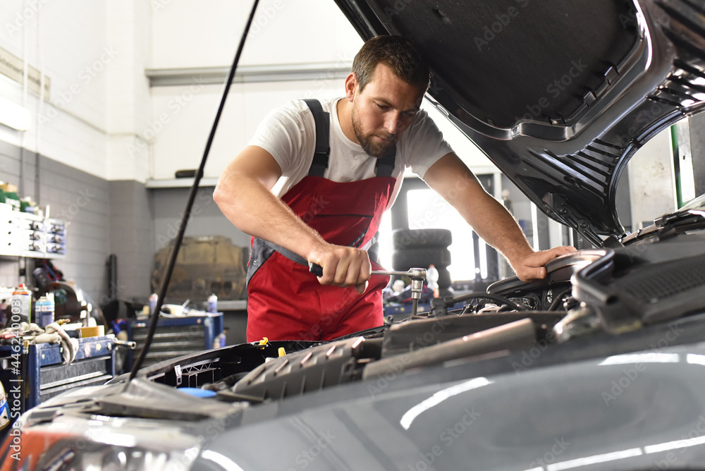 car mechanic in work clothes works in a workshop and repairs a vehicle car mechanic in work clothes works in a workshop and repairs a vehicle