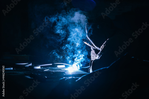 Welder at works close up. White flashes and welding smoke. Metalwork process.