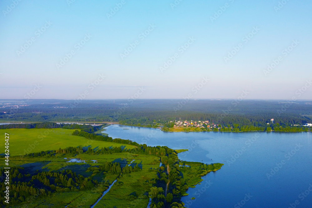 Aerial view of green shore of blue lake on summer morning