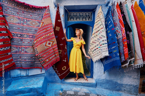 Colorful traveling by Morocco. Young woman in yellow dress walking in  medina of  blue city Chefchaouen. © luengo_ua