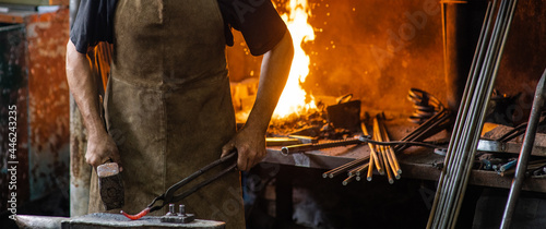 Blacksmith working metal detail with hammer on the anvil in rustic forge. Empty space for text photo