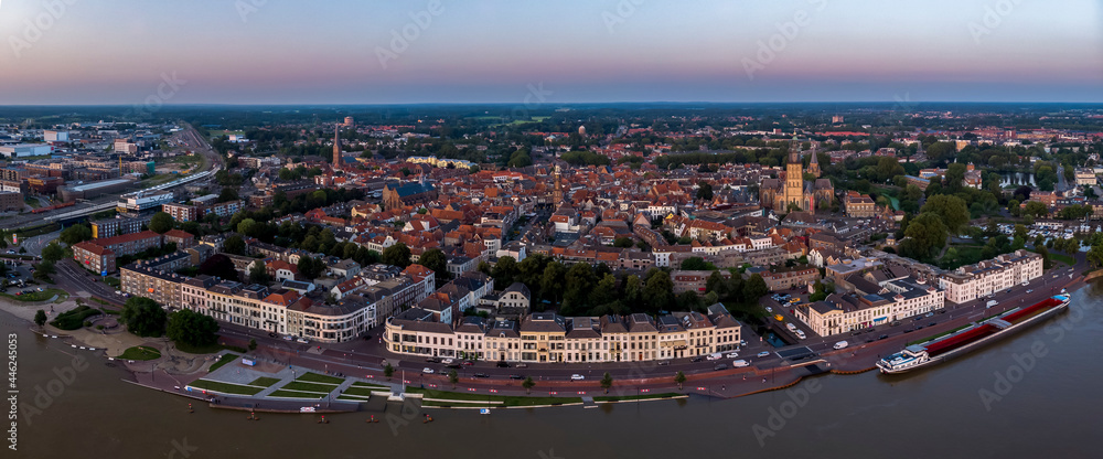 Aerial countenance view of Zutphen, The Netherlands, during sunset with magenta glow on the horizon in the background and high water level in the foreground in front of typical white facades