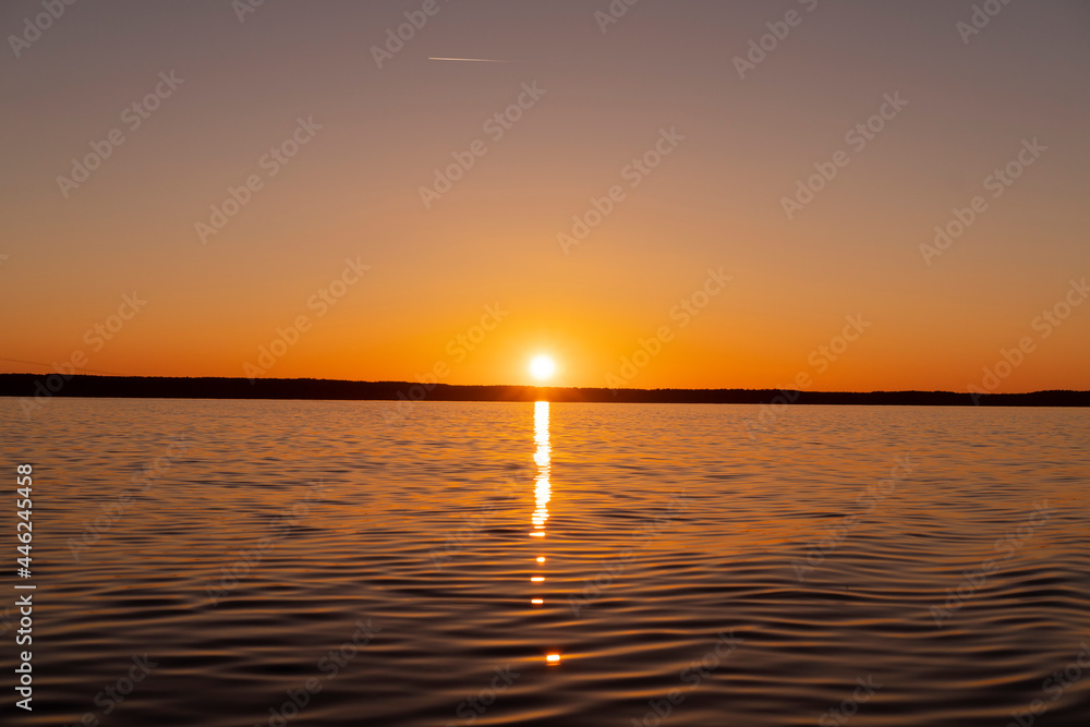 Obraz premium Water surface. View of a Sunset sky background. Dramatic gold sunset sky with evening sky clouds over the sea. View of a Crystal clear sea water texture. Landscape. Small waves. Water reflection