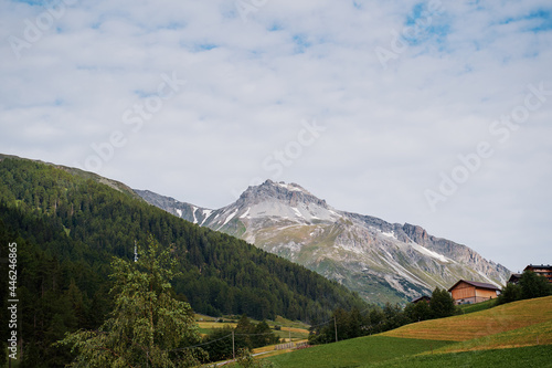 Alpine mountains landscape. Village on green valley land.