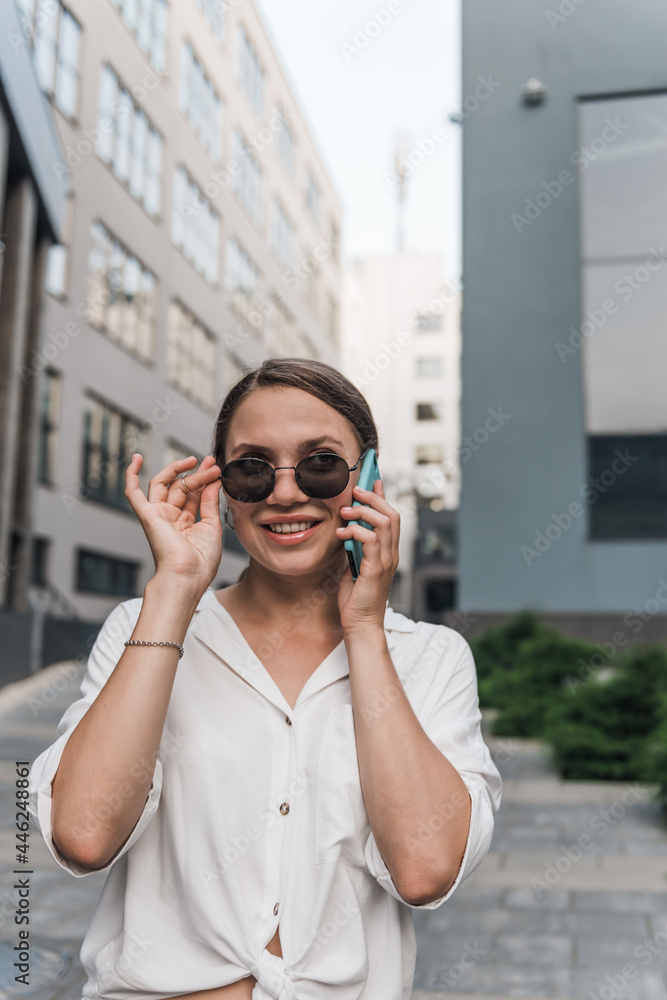 Close up emotion girl walking with smartphone in urban background. Smiling lady holding cellphone in hands outside. 