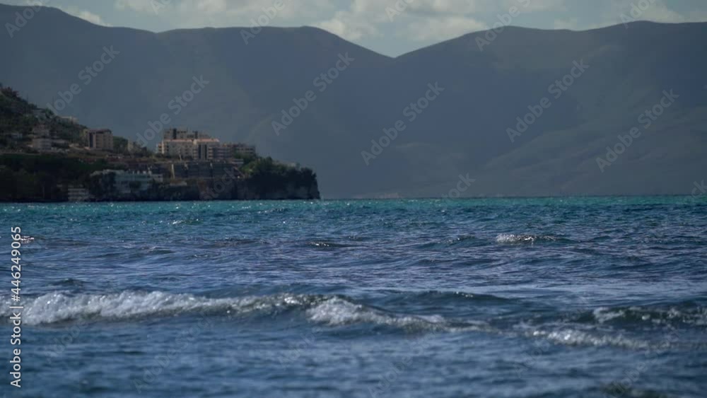 Seascape with sea waves, small city and huge natural mountains on background. Seascape with sea waves, small city and huge natural mountains on background.