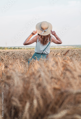 Happy woman with hat in summer field golden wheat, beautiful summer season. Girl enjoying life in colorful field ripe spikelets.
