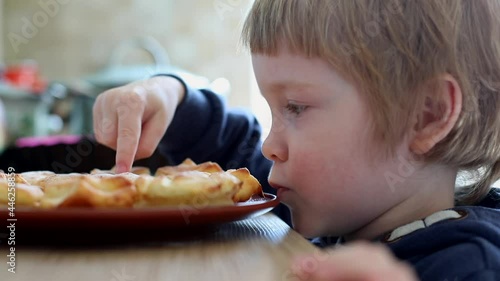 Little caucasian boy smelling sweet baked cheese cakes at home kitchen smiling looking at camera. True kids feelings. Happy childhood. Children nutrition. Family lifestyle. Cooking time together.