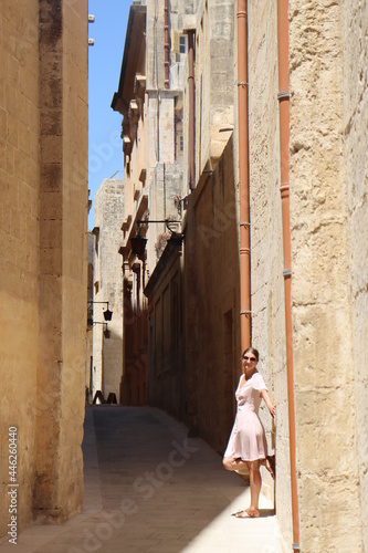 Woman in long dress walking old town of Valletta, sands and ruins tiny square streets © Владислав Порхун
