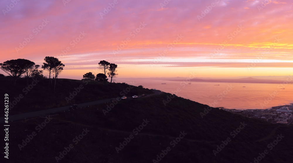 Aerial, drone panoramic of the top of Signal Hill silhouetted against the dawn sky and Table Bay in Cape Town, South Africa.