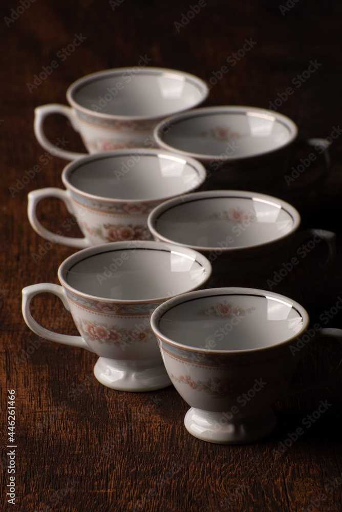 Porcelain cups, beautiful porcelain cups geometrically arranged on rustic wood, dark background, selective focus. Porcelain cups, beautiful porcelain cups geometrically arranged on rustic wood, dark background, selective focus.