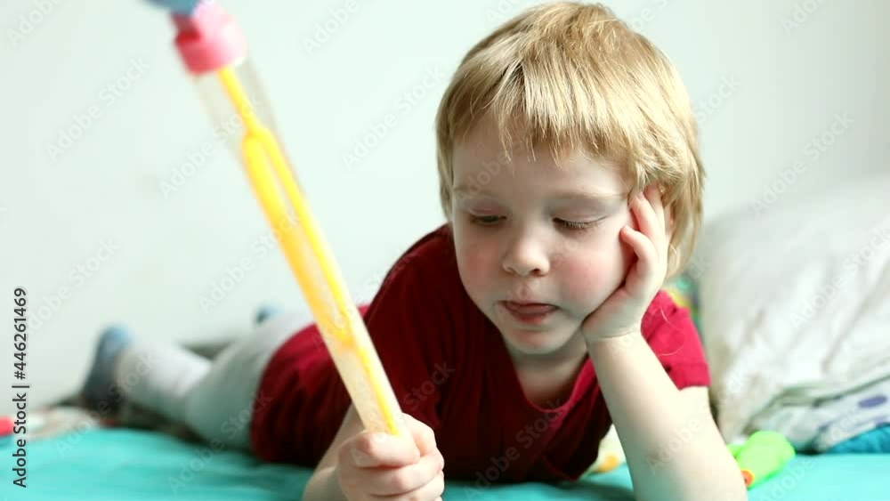 Close-up portrait of little emotional blonde boy playing at home smiling talking looking at camera enjoying happy childhood resting on bed. Excited male child having fun with family indoor. Kids joy. Close-up portrait of little emotional blonde boy playing at home smiling talking looking at camera enjoying happy childhood resting on bed. Excited male child having fun with family indoor. Kids joy.