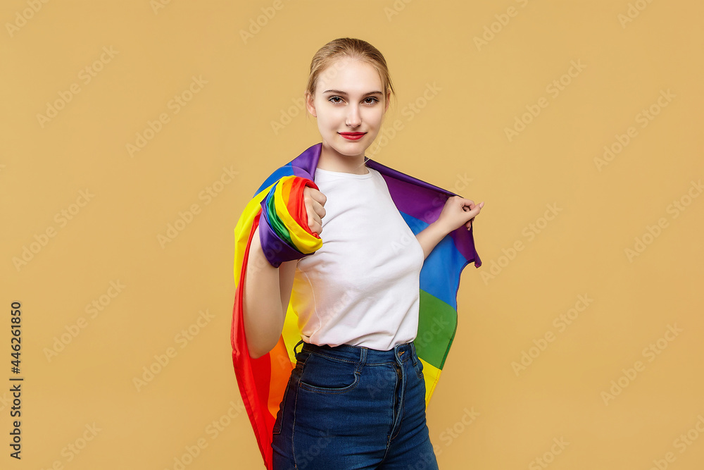 attractive blonde made posing with a rainbow LGBT flag. photo shoot in the studio on a yellow background attractive blonde made posing with a rainbow LGBT flag. photo shoot in the studio on a yellow background