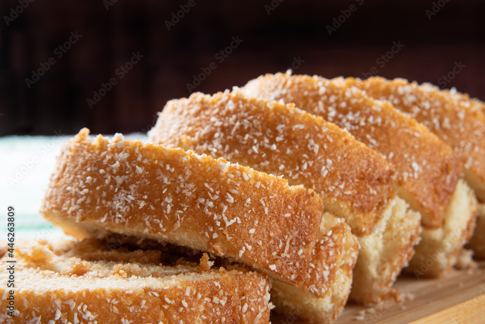 Rocambole, Sliced rocambole stuffed with dulce de leche on a wooden tray on a table with checkered tablecloth. dark background, selective focus. Rocambole, Sliced rocambole stuffed with dulce de leche on a wooden tray on a table with checkered tablecloth. dark background, selective focus.