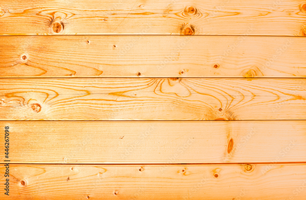 Naklejka premium The texture of wood on the wall of a house made of planed boards. Orange wood wall