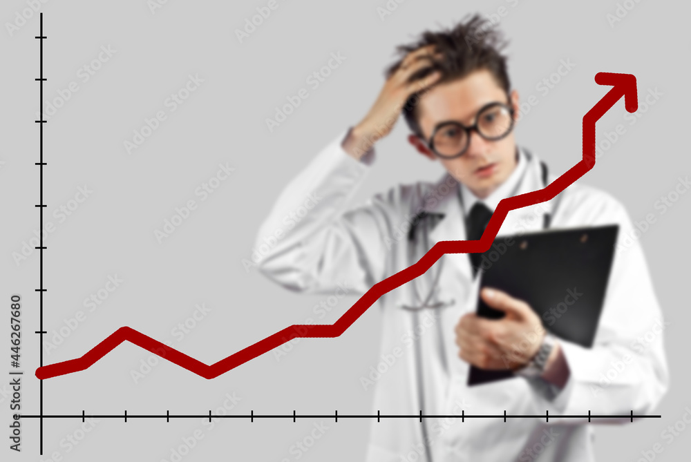 Surprised doctor looks at the growing chart. The concept of increasing morbidity, vaccination and mortality. A man in a doctor's suit on a white background. Surprised doctor looks at the growing chart. The concept of increasing morbidity, vaccination and mortality. A man in a doctor's suit on a white background.
