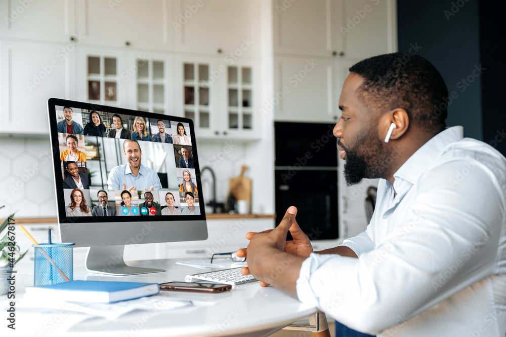 Distant meeting, online communication. African American business man has a virtual meeting with multiracial business colleagues, discussing financial strategy, talking on a video call, brainstorming Distant meeting, online communication. African American business man has a virtual meeting with multiracial business colleagues, discussing financial strategy, talking on a video call, brainstorming
