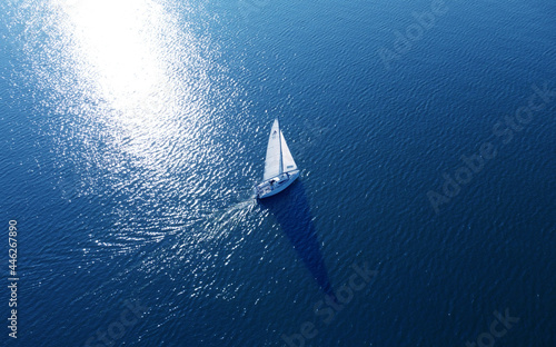 Aerial view of a white yacht with a sail. Ship in the blue sea