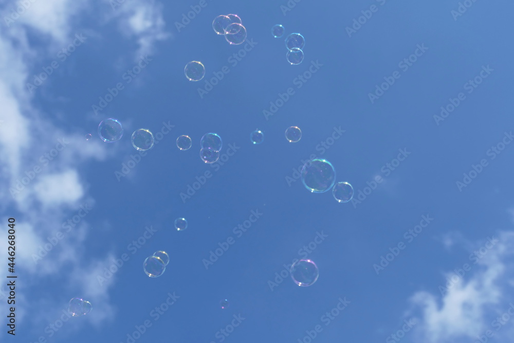 Soap bubbles floating in the air with a blue sky with clouds in the background