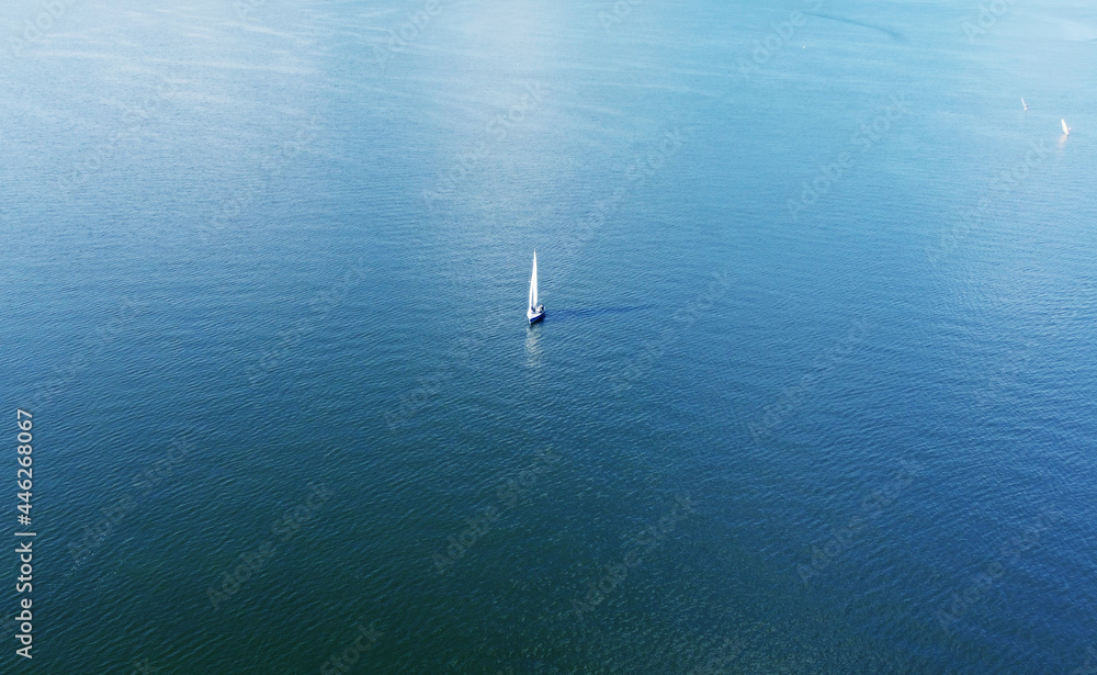 Aerial view of a white yacht with a sail. Ship in the blue sea
