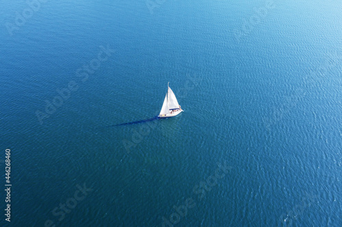 Aerial view of a white yacht with a sail. Ship in the blue sea