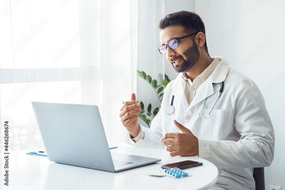 Portrait of indian man doctor talking to online patient on laptop screen Portrait of indian man doctor talking to online patient on laptop screen