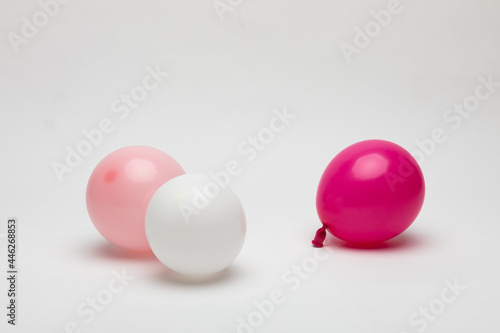 Small balloons in white, pink, and puchisha colors on a white background.