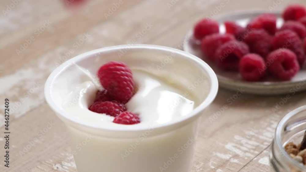 Slow motion raspberries falling in yogurt in plastic jar. Healthy food Slow motion raspberries falling in yogurt in plastic jar. Healthy food